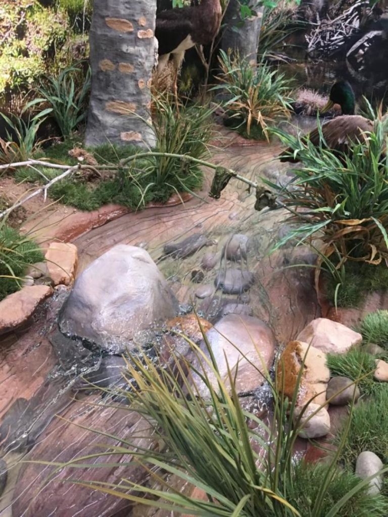 Recreación de agua corriendo entre árboles y rocas.